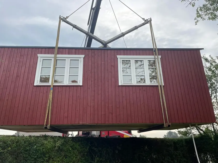 Rødt Penalhus løftes på plads med kran