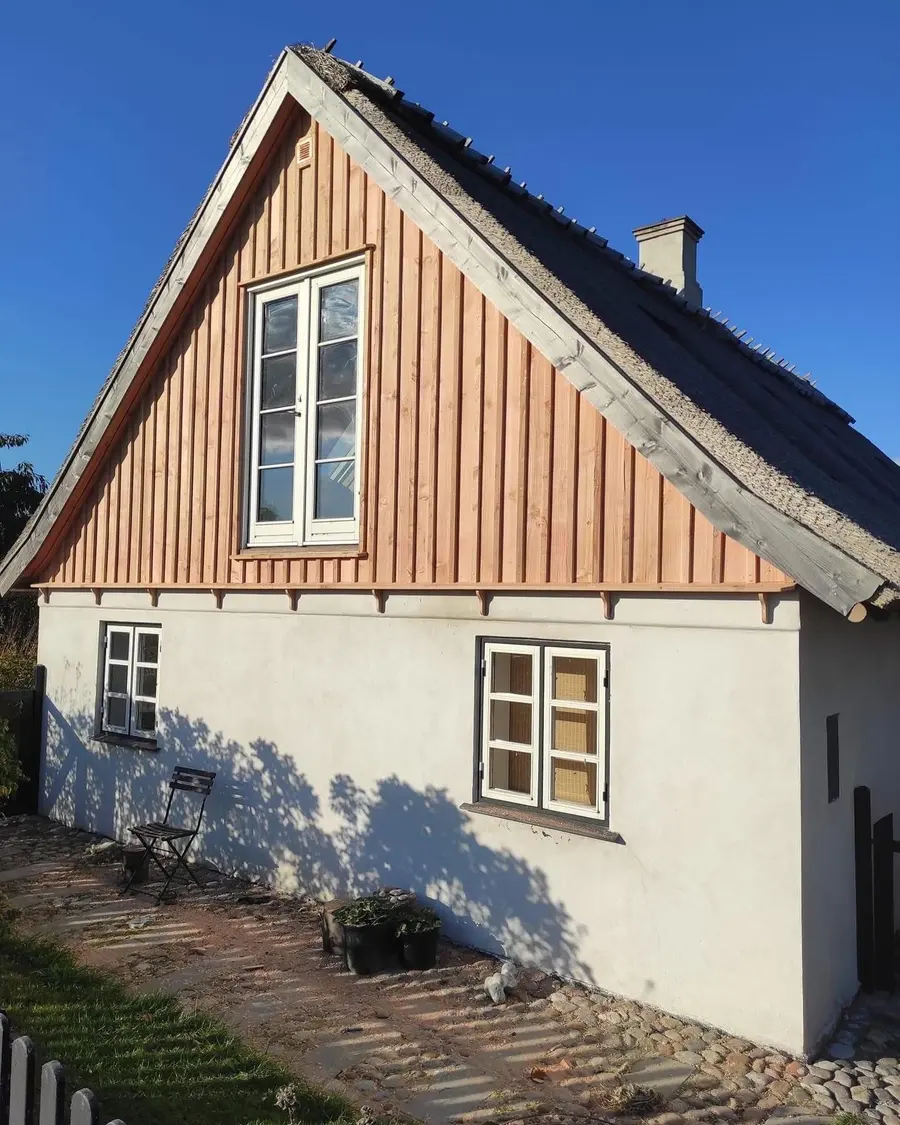 Hvidkalket hus med stråtag og ny træbeklædt gavltrekant